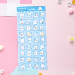 Op de afbeelding: Een vel stickers met een blauwe achtergrond en witte cartoon beer illustraties. De stickers hebben verschillende ontwerpen, waaronder beren met hoeden, brillen en accessoires. De tekst "Snowflake" is zichtbaar.