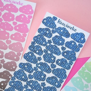 May include: Three sheets of stickers featuring clouds with stars. The first sheet has pink clouds with white stars, the second sheet has blue clouds with white stars, and the third sheet has pastel green clouds with white stars.