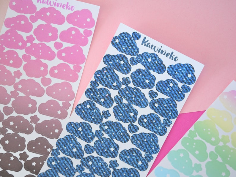 May include: Three sheets of stickers featuring clouds with stars. The first sheet has pink clouds with white stars, the second sheet has blue clouds with white stars, and the third sheet has pastel green clouds with white stars.