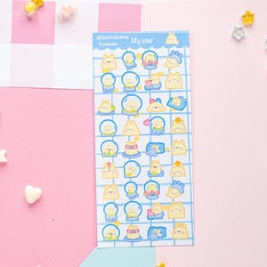 Op de afbeelding: Een vel stickers met verschillende stripfiguren in een blauw rasterpatroon. De stickers tonen gele en blauwe karakters in sneeuwbollen en andere ontwerpen. De tekst "My star" staat bovenaan. Decoratieve ster- en hartvormige versieringen zijn verspreid.