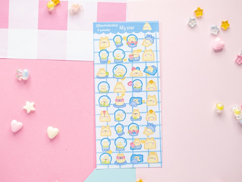 Op de afbeelding: Een vel stickers met verschillende stripfiguren in een blauw rasterpatroon. De stickers tonen gele en blauwe karakters in sneeuwbollen en andere ontwerpen. De tekst "My star" staat bovenaan. Decoratieve ster- en hartvormige versieringen zijn verspreid.