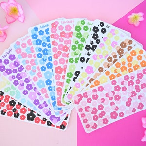 May include: A set of 12 sheets of flower-shaped stickers in various colors, including pink, blue, green, yellow, orange, and black. Each sheet has the word "Kawaii" printed on it.