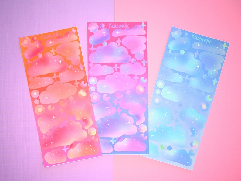 May include: Three sheets of iridescent holographic stickers featuring a cloud and star design. The sheets are pink, blue, and orange with the text "Kawaii" printed on each sheet.