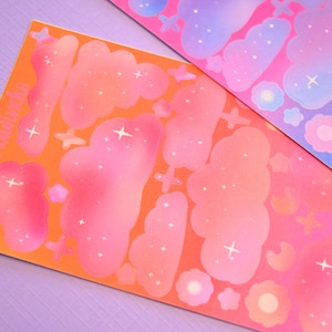 May include: Two sheets of stickers with a celestial theme. The stickers are pink, orange, and blue with white stars and clouds. The text "Kawaii" is printed on one sheet.