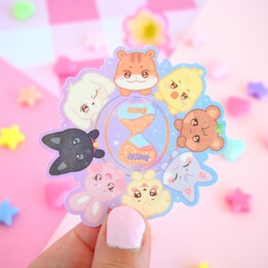 Op de afbeelding: Een stickerblad met een pastelkleurig kleurenschema met een zandloper met sterren en een cirkel van schattige dierengezichten. De dieren zijn een kat, een hond, een konijn, een hamster, een vogel en een beer.