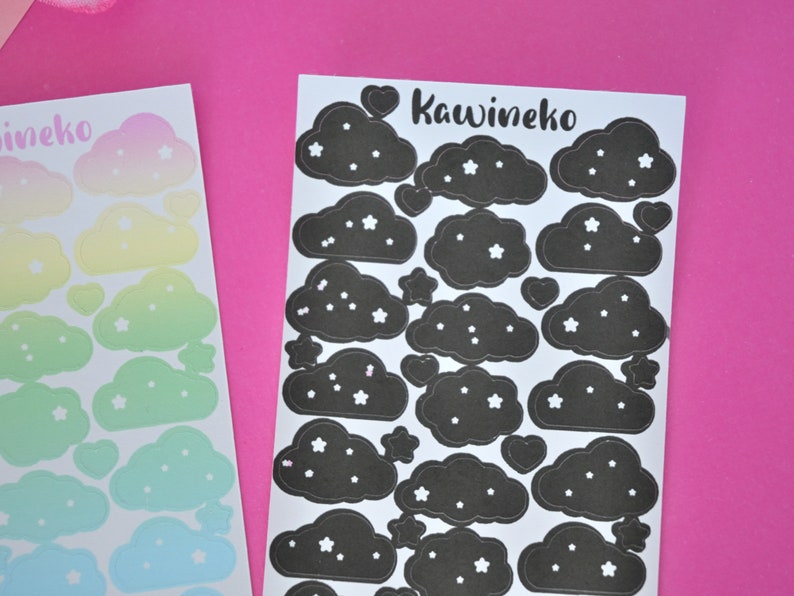 May include: Two sheets of stickers featuring black clouds with white stars. The sheet on the right has the text "Kawineko" in black cursive lettering.