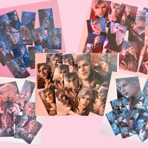 May include: A collection of rectangular art cards featuring a character with silver hair and blue eyes. The cards display various poses and expressions of the character, with a mix of dark and light backgrounds. The cards are arranged on a pink surface.
