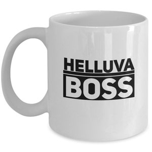 Puede incluir: Taza de café de cerámica blanca con texto negro que dice "Helluva Boss".