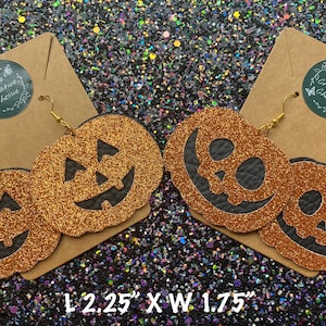 May include: A pair of orange glitter pumpkin earrings with black jack-o'-lantern faces. The earrings are 2.25 inches long and 1.75 inches wide.