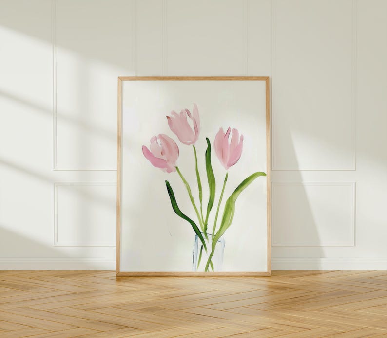 May include: A framed watercolor painting of pink tulips in a glass vase. The tulips are painted in a loose, abstract style, with soft, flowing lines. The background is a simple white.