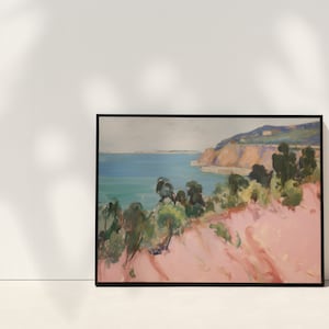 May include: A framed landscape painting featuring a coastal scene with a pink foreground, green trees, and a blue ocean meeting a distant cliffside under a pale sky. The artwork is enclosed in a thin black frame, displaying expressive brushstrokes.
