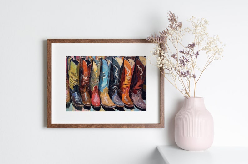 May include: A framed art print featuring a row of colorful cowboy boots in shades of yellow, orange, red, blue, and brown. The boots are depicted with detailed stitching and pointed toes, arranged side-by-side in a vibrant, painterly style.