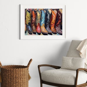 May include: A framed wall art print featuring a colorful painting of a row of cowboy boots in various shades including yellow, red, blue, black, orange, and brown. The artwork is displayed in a white frame, showcasing detailed brushstrokes.