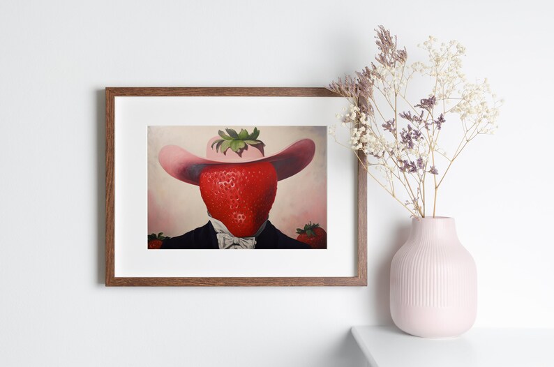 Peut inclure: Une impression d'art encadr&eacute;e repr&eacute;sentant une illustration surr&eacute;aliste d'une grosse fraise rouge portant un chapeau de cow-boy rose et une veste de costume noire avec une chemise blanche &agrave; col et un n&oelig;ud papillon sur fond rose p&acirc;le.