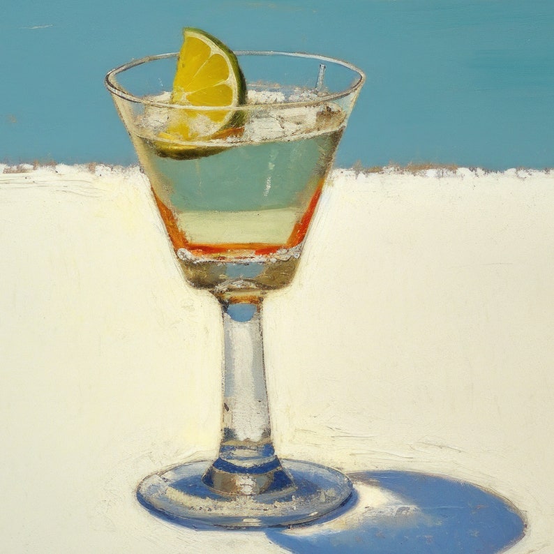 May include: A clear glass cocktail glass with a lime wedge garnish, filled with a light yellow liquid. The glass has a thin, clear stem and a wide, round base. The glass is sitting on a white surface.