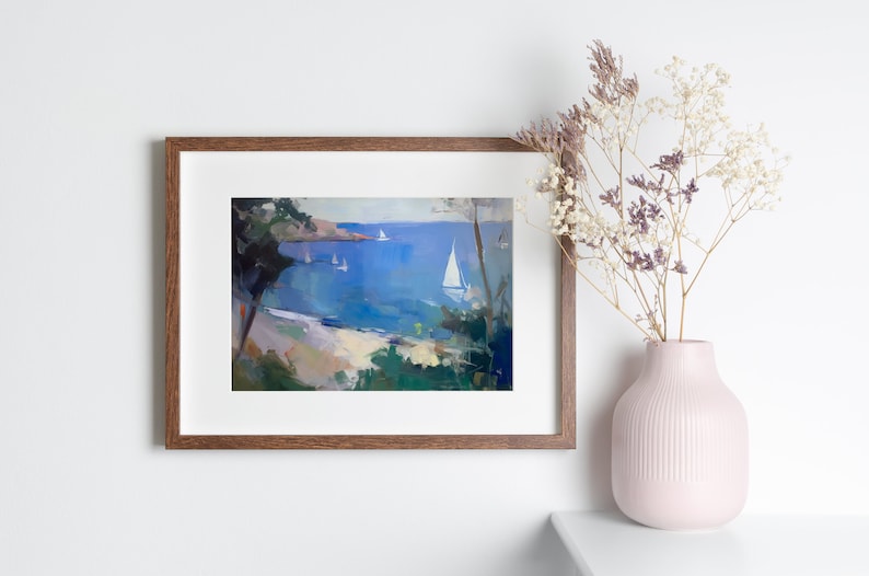 May include: A framed painting of a seascape with a sailboat in the foreground and a coastline in the background. The painting is in a brown frame and is hanging on a white wall.
