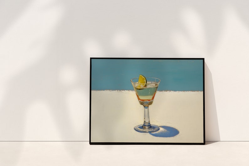May include: A framed painting of a martini glass with a lime wedge on a white surface against a blue background.