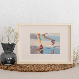 Peut inclure: Un cadre rectangulaire en bois clair contenant une impression d'une peinture repr&eacute;sentant des jambes portant des patins &agrave; glace rouges sur une surface r&eacute;fl&eacute;chissante. Le cadre est plac&eacute; &agrave; c&ocirc;t&eacute; d'un vase en verre gris fonc&eacute; avec des fleurs blanches.