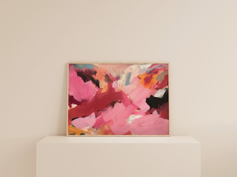 May include: Abstract painting with a wooden frame. The artwork features a vibrant mix of pink, red, black, and orange brushstrokes. The painting is displayed on a white surface, creating a modern aesthetic.