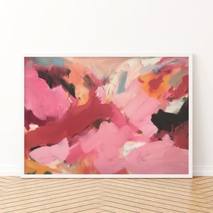 May include: Abstract art print in a white frame. The artwork features a vibrant mix of pink, red, orange, and black brushstrokes. The painting has a textured appearance, with visible layers of paint. The overall style is modern and expressive, suitable for home decor.