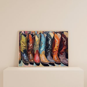 May include: A framed painting depicting a row of seven cowboy boots in various colors including lime green, orange, yellow, blue, black, and dark red. The artwork features visible brushstrokes and a textured style, showcasing the distinct shapes.