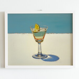May include: A framed painting of a martini glass with a lime wedge on a white surface against a blue background.
