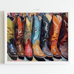 May include: An oil painting in a white frame depicting a row of colorful cowboy boots. The boots are rendered in vibrant shades of yellow, orange, red, blue, black, and brown, featuring visible brushstrokes and detailed stitching patterns.