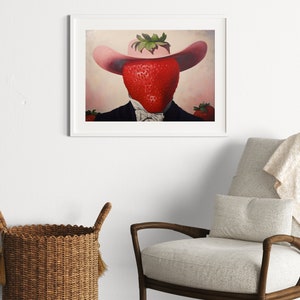 Peut inclure: Une impression d'art encadr&eacute;e repr&eacute;sentant le portrait surr&eacute;aliste d'une grosse fraise rouge portant un chapeau rose &agrave; larges bords et un costume sombre avec un n&oelig;ud papillon blanc. La fraise est centr&eacute;e, avec des fraises plus petites sur les c&ocirc;t&eacute;s.
