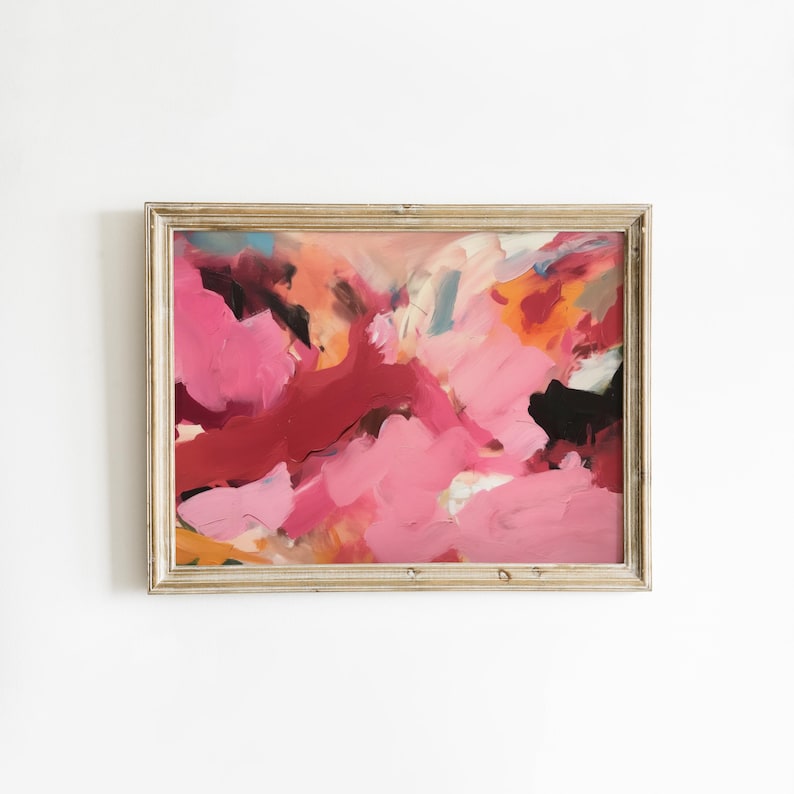 May include: Abstract painting in a gold-toned wooden frame. The artwork features bold brushstrokes in shades of pink, red, orange, and black. The composition is dynamic and expressive, with a focus on color and texture. The painting is mounted on a white wall.