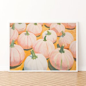 Op de afbeelding: Een ingelijst schilderij met een verzameling lichtroze en witte pompoenen met groene stelen, gerangschikt op een levendige gele achtergrond. Het kunstwerk toont meerdere kalebassen in verschillende maten, weergegeven met zichtbare penseelstreken.