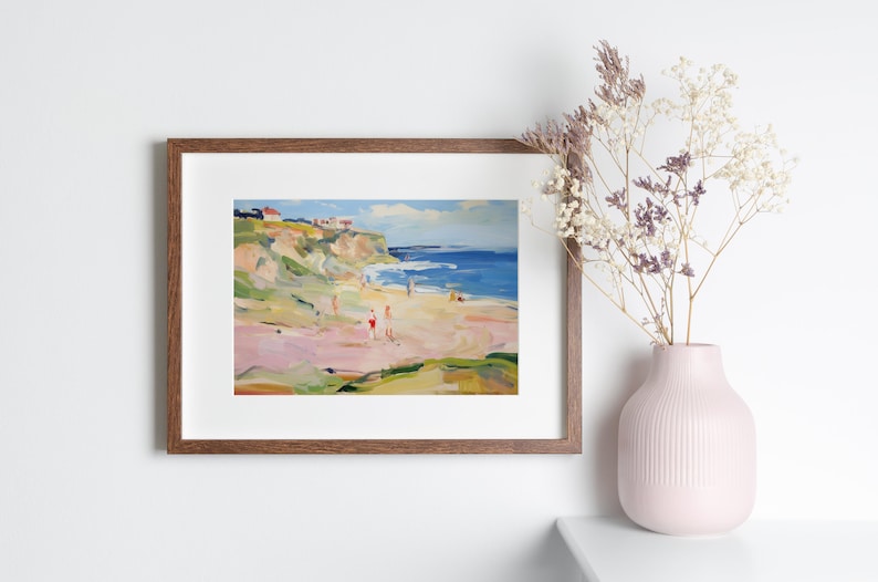 Puede incluir: Una pintura enmarcada de una escena de playa con un acantilado en el fondo. La pintura est&aacute; realizada en un estilo suelto e impresionista con colores brillantes. La playa es rosa y el agua es azul. Hay gente en la playa y en el agua.