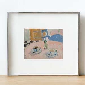May include: A framed print of an oil painting depicting a pink circular table with two teacups on saucers and a small glass vase with flowers. The scene includes a blue chair, a checkered floor, and a wooden cabinet in the background.
