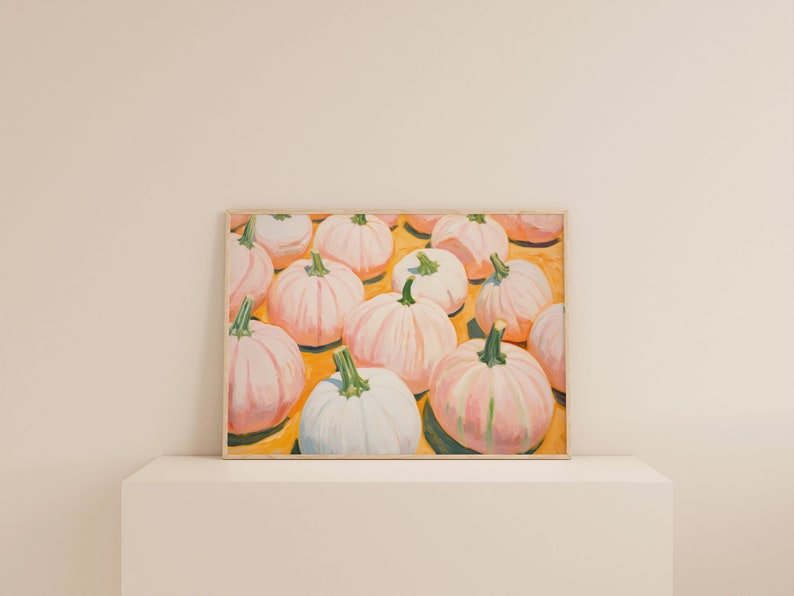Op de afbeelding: Een rechthoekig ingelijst schilderij met een verzameling lichtroze en witte pompoenen met groene stelen, gerangschikt op een felgeel oppervlak. Het kunstwerk toont meerdere pompoenen van verschillende groottes, weergegeven met zichtbare penseelstreken en zachte highlights.