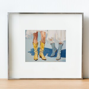 May include: A framed painting of two pairs of legs wearing boots. One pair is wearing yellow cowboy boots and the other pair is wearing light blue boots. The background is a light blue color.