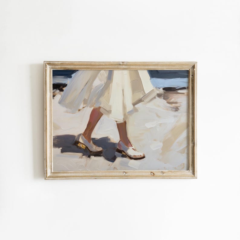 May include: An oil painting in a light wood frame depicting the lower half of a person wearing a flowing cream-colored skirt and white shoes. The scene shows the legs and feet walking across a sandy surface with visible brushstrokes in shades of white, beige, and dark blue, capturing a sense of movement and light.