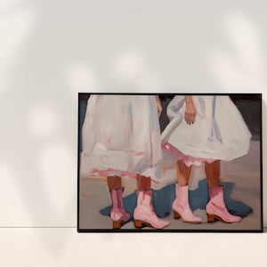 May include: Painting of two people wearing white dresses and pink boots. The painting is framed in black.