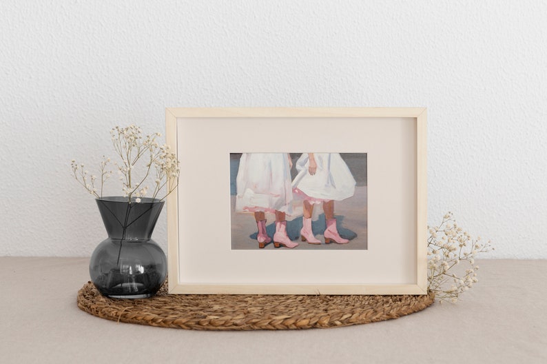May include: A framed painting of two girls wearing white dresses and pink boots. The girls are standing side by side and their legs are crossed at the ankles.