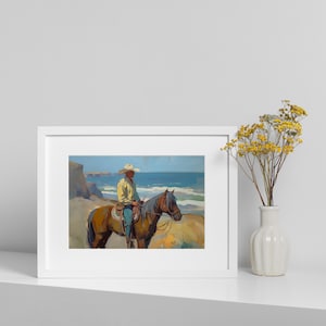 Pu&ograve; includere: Opera d'arte incorniciata raffigurante un cowboy a cavallo sulla spiaggia. Il dipinto mostra un uomo con cappello da cowboy e camicia gialla, che cavalca un cavallo marrone. L'oceano e le scogliere sullo sfondo. Un vaso di fiori gialli a destra.