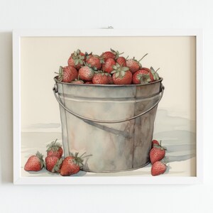 May include: A watercolor painting of a metal bucket filled with ripe red strawberries. The bucket is sitting on a white surface with a few strawberries scattered around it.