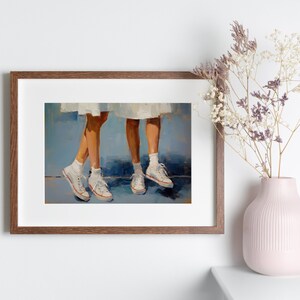 May include: A framed painting depicting two pairs of legs wearing white trainers. The legs are set against a blue background.