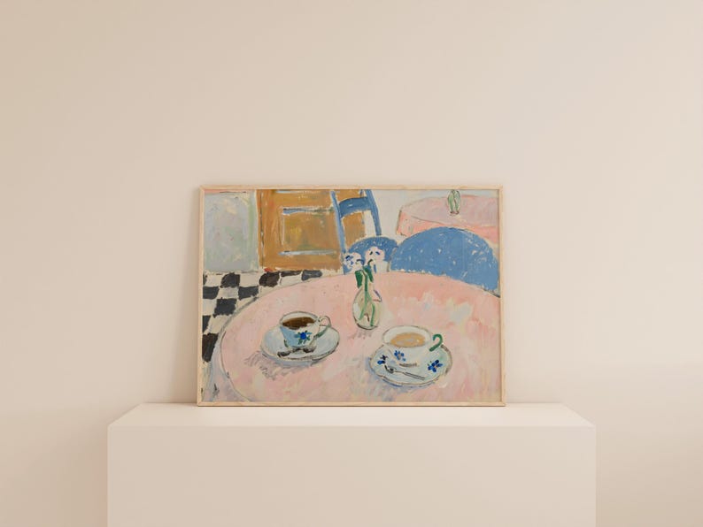May include: A framed rectangular art print depicting a painted interior scene with a round pink table, two teacups on saucers, and a small vase with flowers. The background features a black and white checkered floor, a blue chair, and a wooden cabinet.