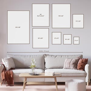 May include: A living room interior design mockup with a gray sofa and a coffee table. The wall is decorated with a gallery wall of framed artwork in various sizes. The artwork is all white and the frames are black. The sofa is 72 inches wide. The measurements of the artwork are listed in inches.