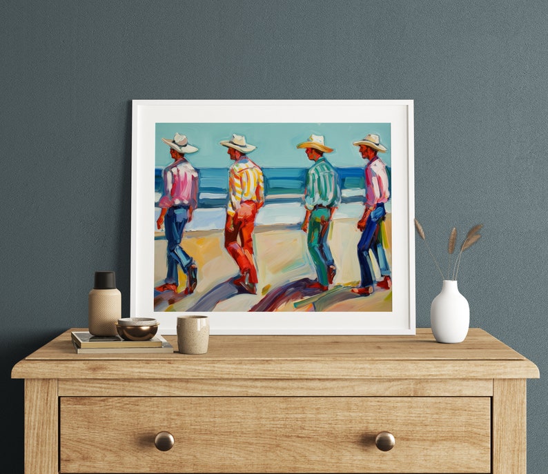 May include: A framed painting depicts four figures in cowboy hats and colorful shirts walking along a beach. The figures are painted in bright hues of pink, yellow, green, and red, with blue jeans. The ocean and sky are visible in the background.