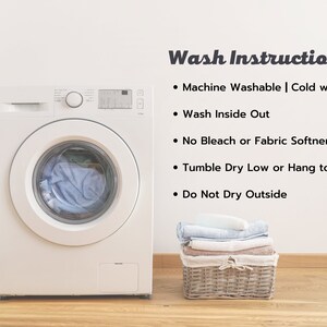 May include: White washing machine with a blue towel inside the drum.  Wash instructions are listed on a white wall: Machine Washable | Cold water, Wash Inside Out, No Bleach or Fabric Softner, Tumble Dry Low or Hang to Dry, Do Not Dry Outside.