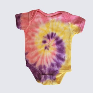 May include: A pink, yellow, and purple tie-dye baby onesie with a spiral pattern.