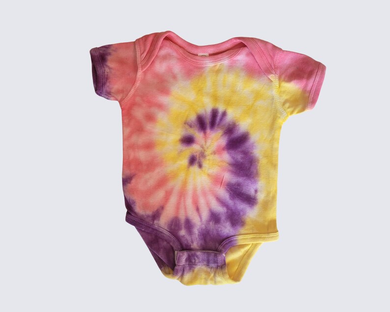 May include: A pink, yellow, and purple tie-dye baby onesie with a spiral pattern.