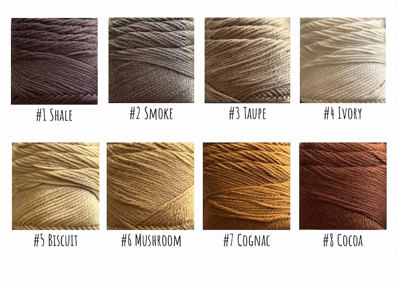 Pode incluir: Um gr&aacute;fico de cores com oito amostras de fios em v&aacute;rias tonalidades. As cores variam do castanho escuro (#1 Shale) ao bege claro (#4 Ivory) e incluem tons de cinza, bege e dourado. Cada amostra &eacute; rotulada com um n&uacute;mero e um nome de cor.