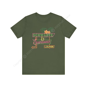 Könnte beinhalten: Grünes T-Shirt mit einem Neon-Schild-Motiv, auf dem "Schwartz & Scandovals Lounge" steht. Das Schild ist mit rosa Blumen und grünen Blättern verziert.