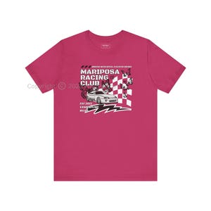May include: Pink t-shirt with a black and white graphic design featuring a car, butterflies, and the text "Mariposa Racing Club, Est 2013, Vanderpump Rules".