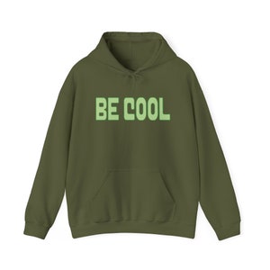 Puede incluir: Una sudadera con capucha verde con el texto "BE COOL" en verde claro.